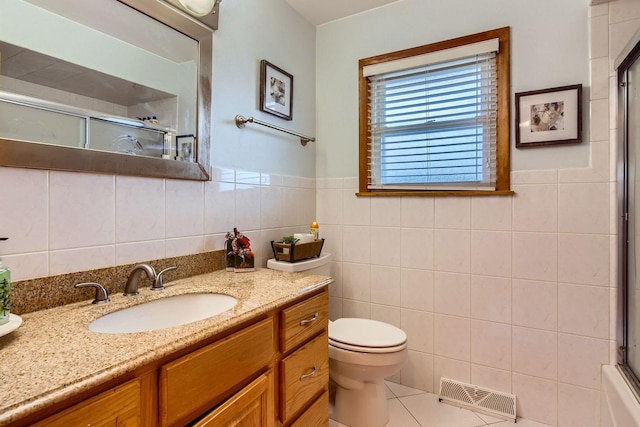 bathroom with toilet, vanity, tile patterned floors, and tile walls