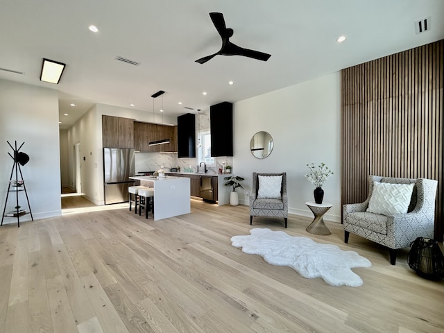 living room with ceiling fan, sink, and light hardwood / wood-style flooring