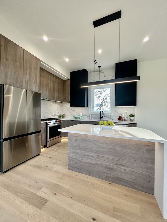 kitchen featuring pendant lighting, light wood-type flooring, tasteful backsplash, and appliances with stainless steel finishes