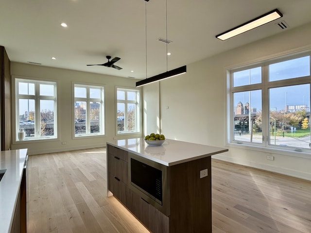 kitchen featuring built in microwave, a wealth of natural light, a center island, and pendant lighting