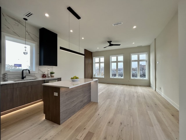 kitchen featuring pendant lighting, light hardwood / wood-style floors, a center island, and sink