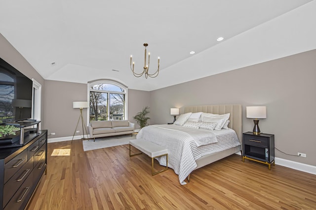 bedroom with light hardwood / wood-style floors, a chandelier, and vaulted ceiling