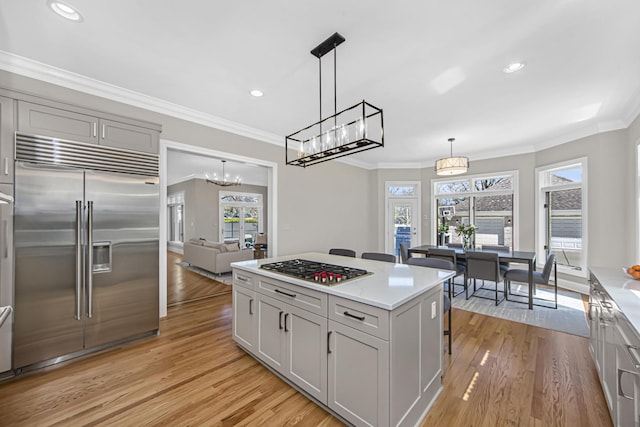 kitchen with ornamental molding, appliances with stainless steel finishes, decorative light fixtures, and gray cabinets