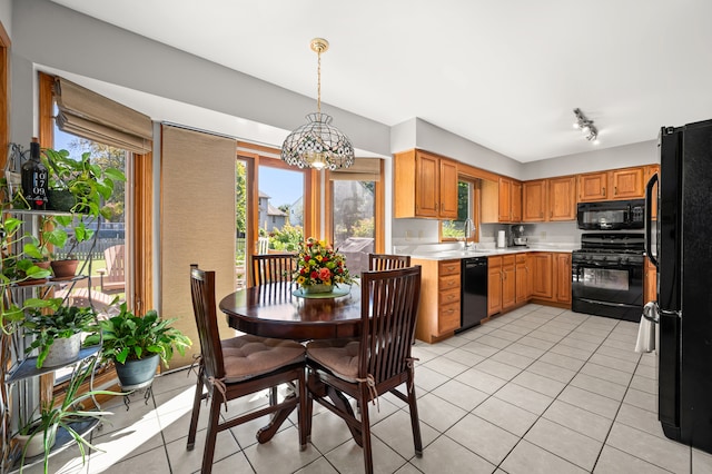 kitchen featuring sink, light tile patterned floors, black appliances, and decorative light fixtures