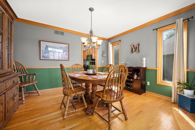 dining area featuring light wood-type flooring, an inviting chandelier, and ornamental molding