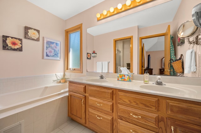 bathroom with tile patterned floors, vanity, and tiled bath