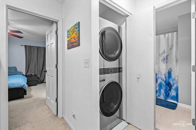 washroom featuring ceiling fan, stacked washer / dryer, and light colored carpet