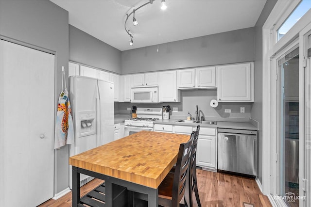 kitchen with white cabinetry, sink, white appliances, and light wood-type flooring