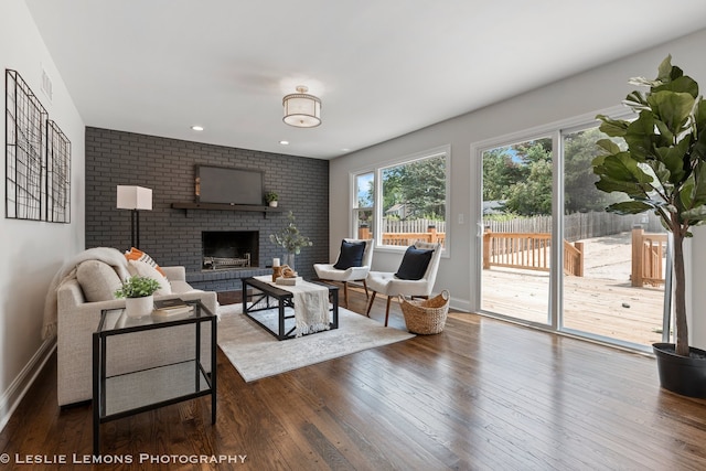 living room featuring wood-type flooring and a brick fireplace