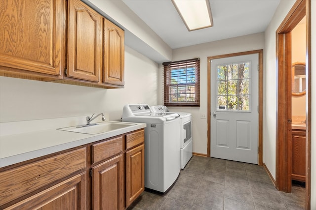 clothes washing area featuring washing machine and dryer, sink, and cabinets