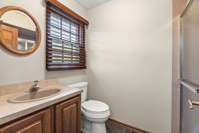 bathroom with tile patterned flooring, vanity, a shower with door, and toilet