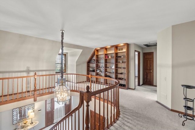 hall featuring light colored carpet and an inviting chandelier