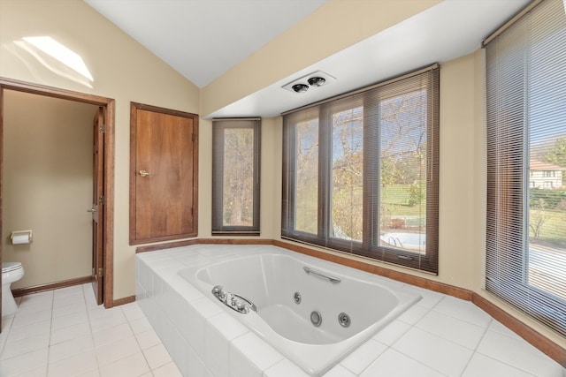 bathroom featuring tile patterned floors, toilet, lofted ceiling, and tiled tub