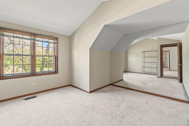 additional living space with light carpet and vaulted ceiling