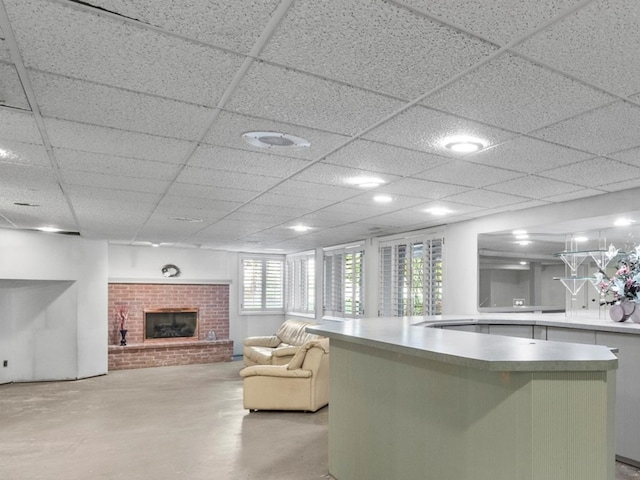 interior space featuring kitchen peninsula, a paneled ceiling, and a brick fireplace