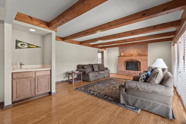 living room with a fireplace, sink, a wealth of natural light, and light hardwood / wood-style flooring