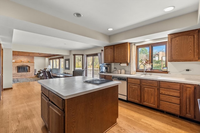 kitchen with dishwasher, sink, a fireplace, a kitchen island, and light wood-type flooring