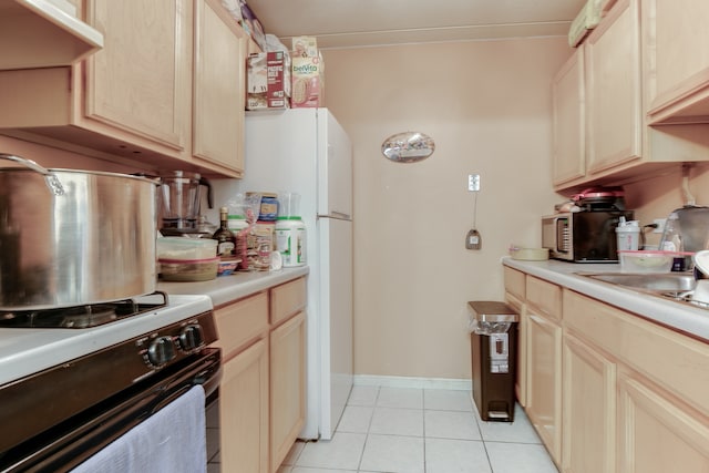 kitchen with light tile patterned flooring, range, white refrigerator, and light brown cabinets