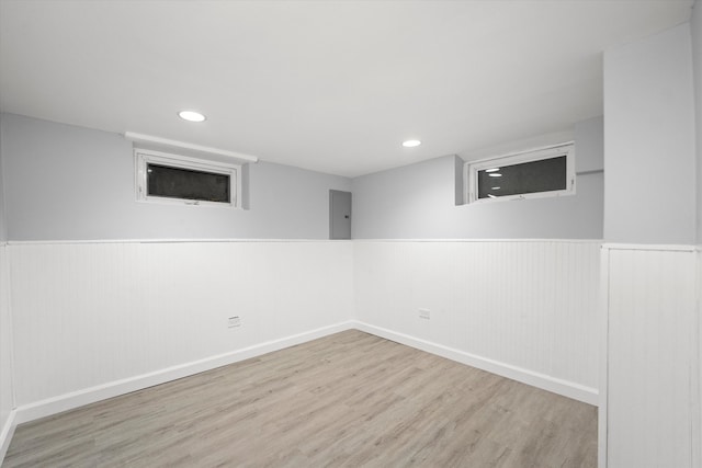 basement with light wood-type flooring and electric panel