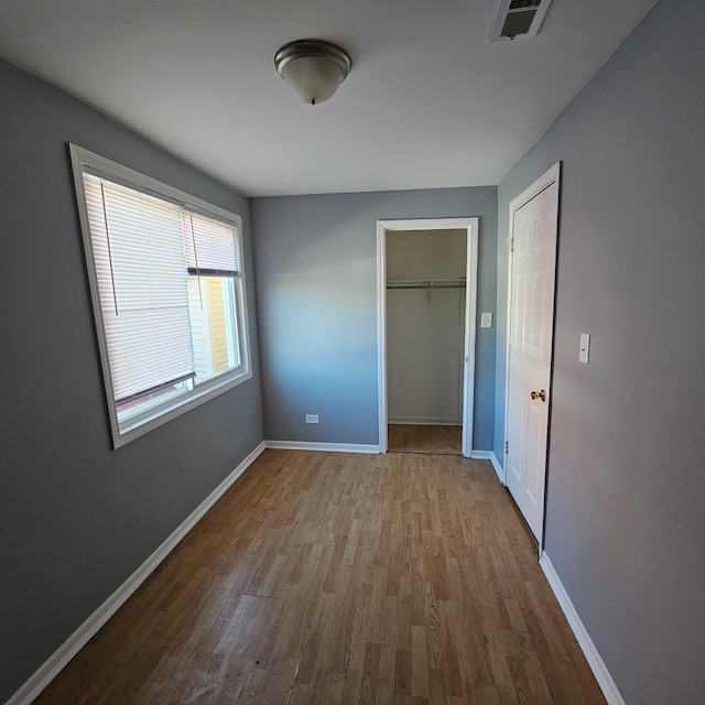 unfurnished bedroom with a closet, a spacious closet, and light hardwood / wood-style flooring