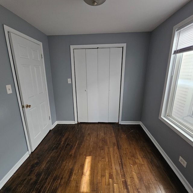 unfurnished bedroom featuring a closet and dark wood-type flooring