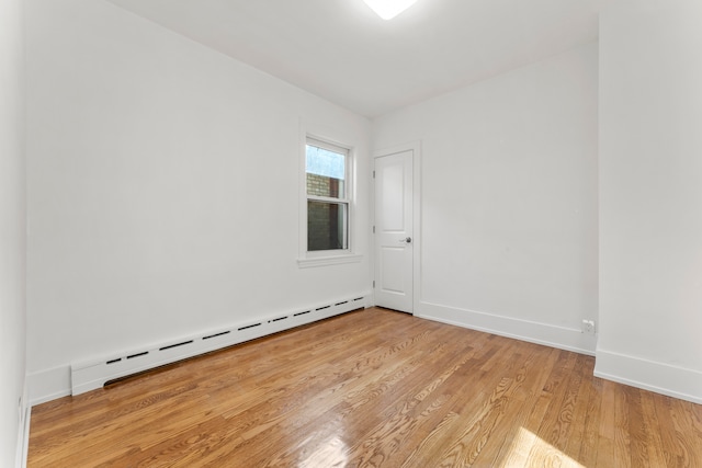 spare room with baseboard heating and light hardwood / wood-style flooring