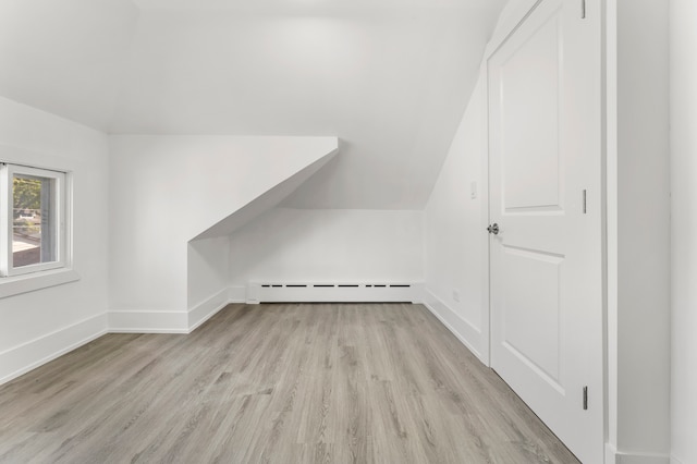 additional living space featuring baseboard heating, lofted ceiling, and light wood-type flooring