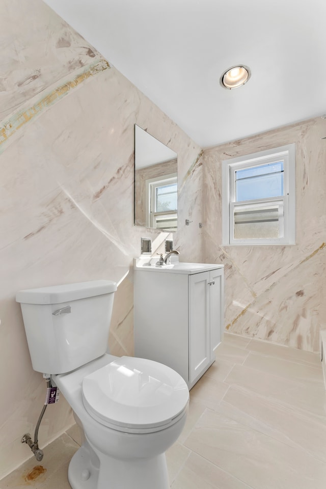 bathroom with vanity, tile walls, and toilet