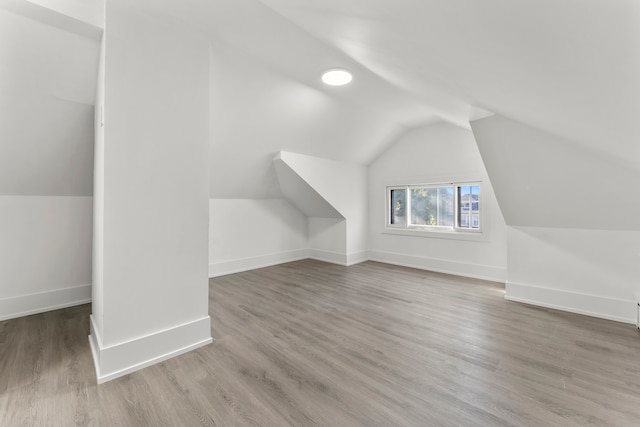 additional living space featuring hardwood / wood-style flooring and vaulted ceiling