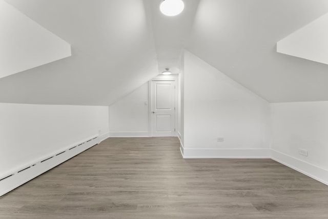 additional living space featuring a baseboard radiator, lofted ceiling, and wood-type flooring