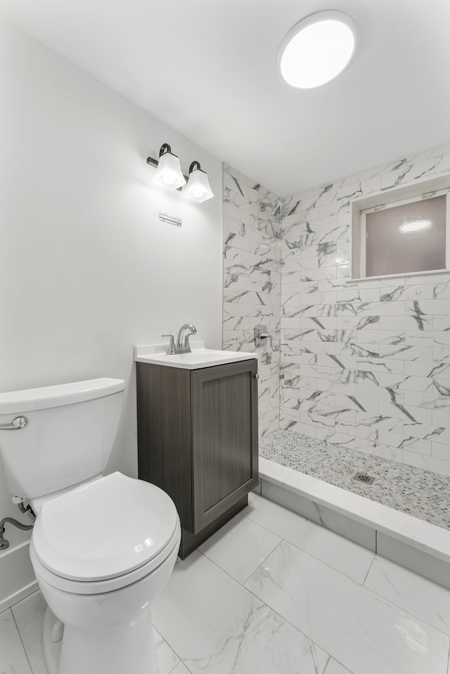 bathroom with a tile shower, vanity, and toilet