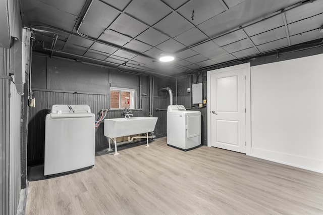 clothes washing area featuring light wood-type flooring, separate washer and dryer, and sink