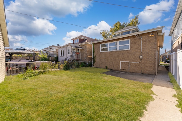 back of house with a gazebo and a lawn