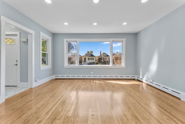 interior space featuring baseboard heating, a wealth of natural light, and light hardwood / wood-style floors