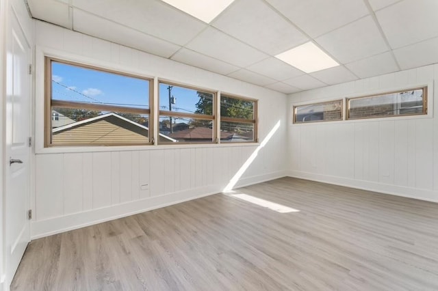 spare room featuring light wood-type flooring and a paneled ceiling