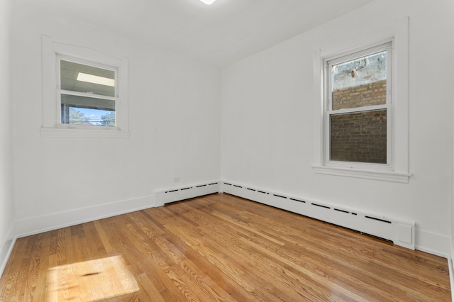 unfurnished room featuring light hardwood / wood-style flooring and a baseboard heating unit