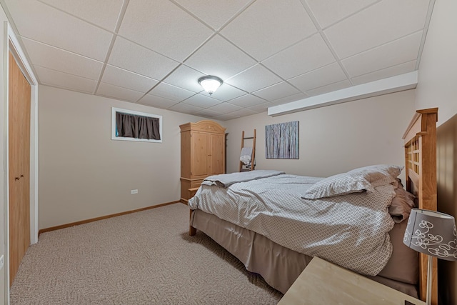 carpeted bedroom featuring a paneled ceiling and a closet