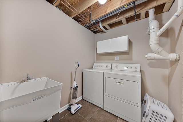 laundry area featuring cabinets, dark tile patterned floors, washer and clothes dryer, and sink