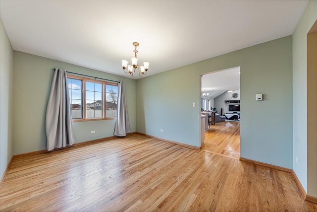 empty room featuring a notable chandelier and light hardwood / wood-style flooring