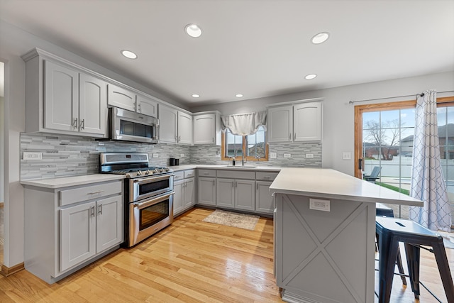 kitchen featuring appliances with stainless steel finishes, light hardwood / wood-style floors, plenty of natural light, and a breakfast bar area