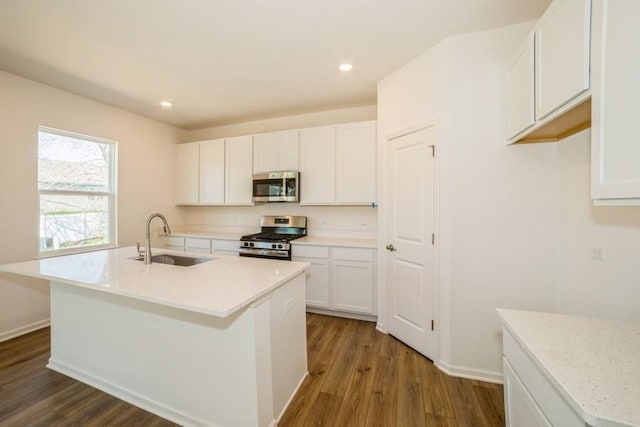 kitchen featuring appliances with stainless steel finishes, dark wood-type flooring, sink, a center island with sink, and white cabinetry