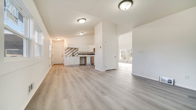 unfurnished room with light hardwood / wood-style floors and vaulted ceiling