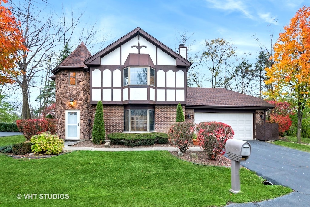 english style home featuring a garage and a front lawn