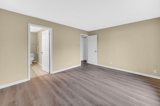 unfurnished bedroom with light wood-type flooring and ensuite bath