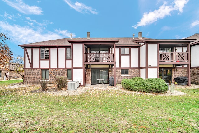 back of property featuring a lawn, a balcony, and central air condition unit