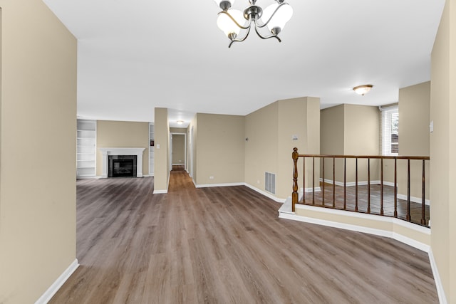 unfurnished living room with light wood-type flooring and an inviting chandelier