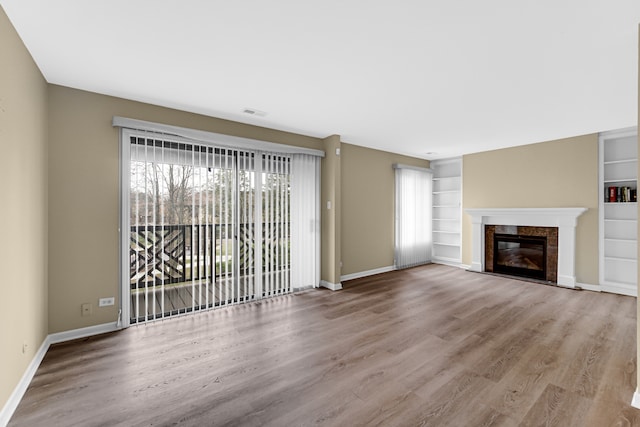 unfurnished living room featuring hardwood / wood-style flooring and built in features