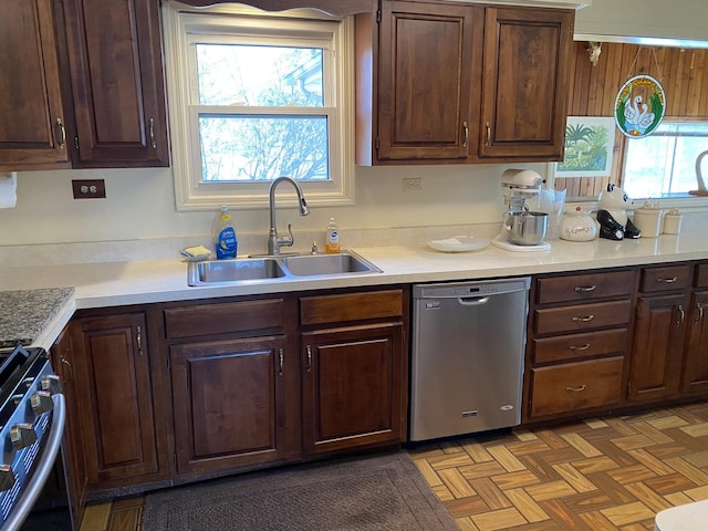 kitchen with dark brown cabinetry, sink, appliances with stainless steel finishes, and light parquet floors