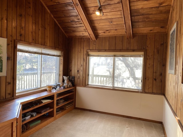 interior space with lofted ceiling with beams, wooden walls, light colored carpet, and wooden ceiling