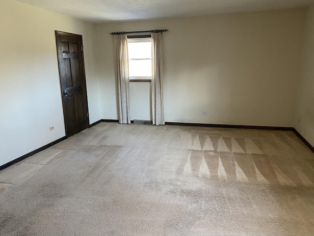 spare room featuring light carpet and a textured ceiling